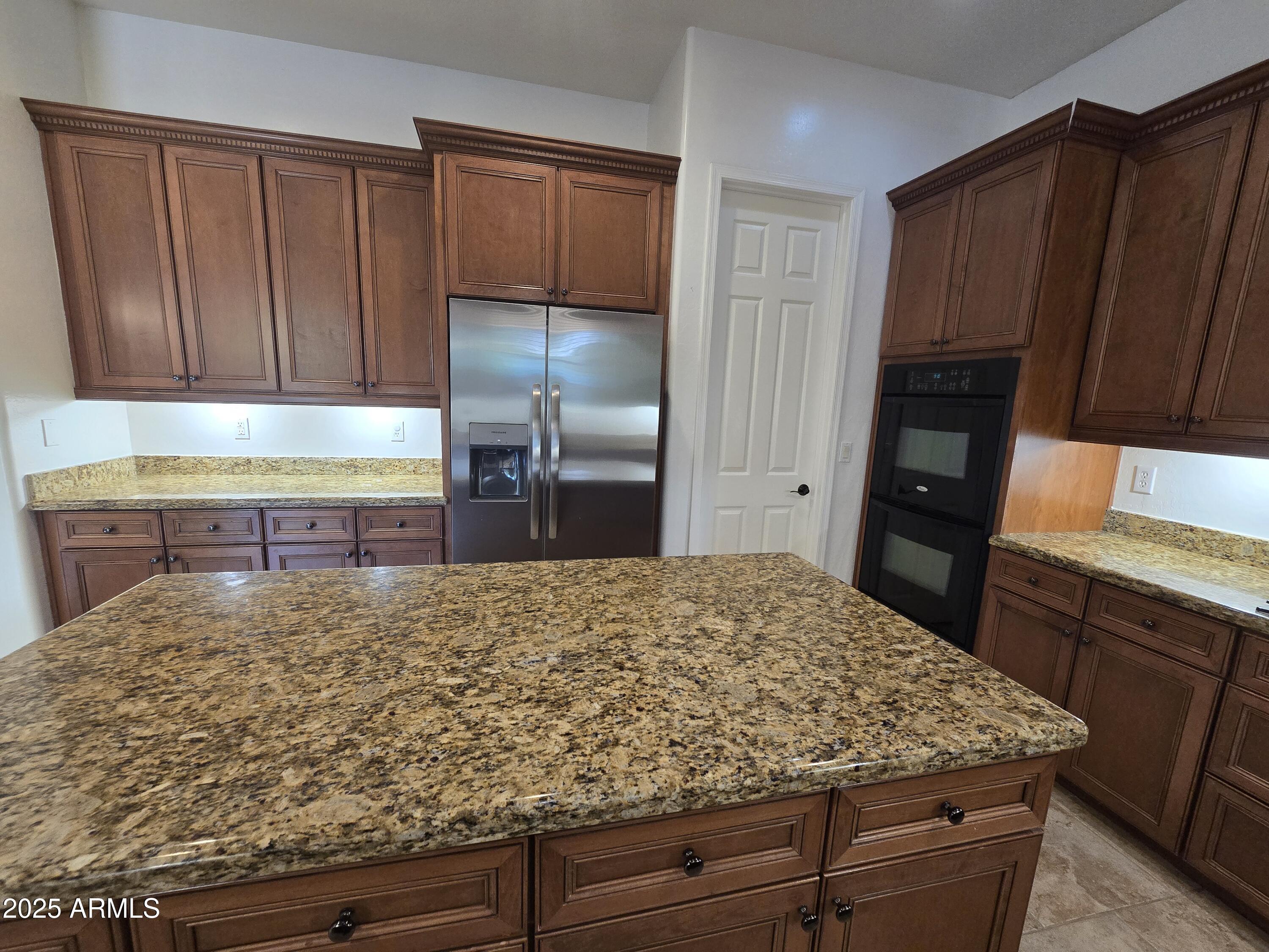6335 South Roanoke Street Gilbert, AZ 85298 - Photo 9 of 36 a kitchen with wooden cabinets and a refrigerator