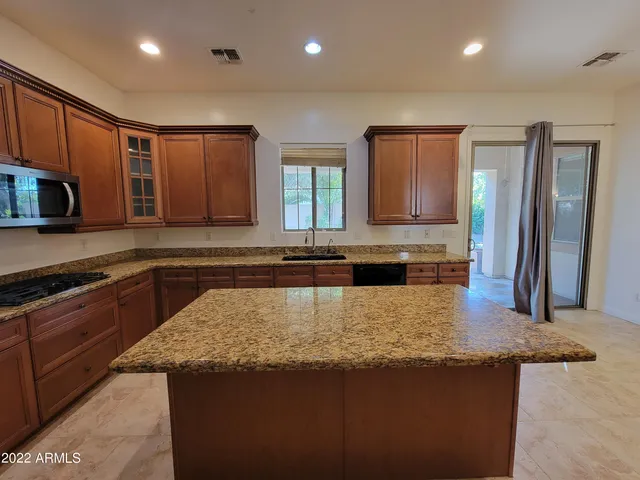 a kitchen with kitchen island granite countertop wooden cabinets a refrigerator and a sink