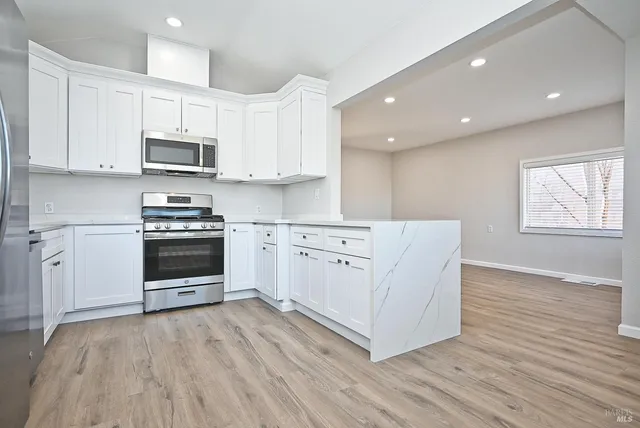 a kitchen with white cabinets and appliances