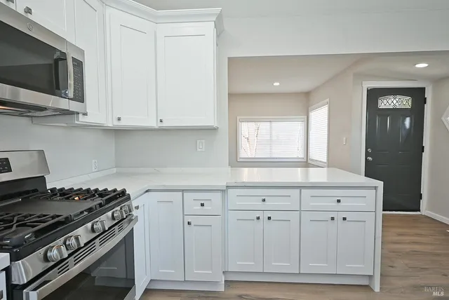 a kitchen with a refrigerator a stove top oven and white cabinets