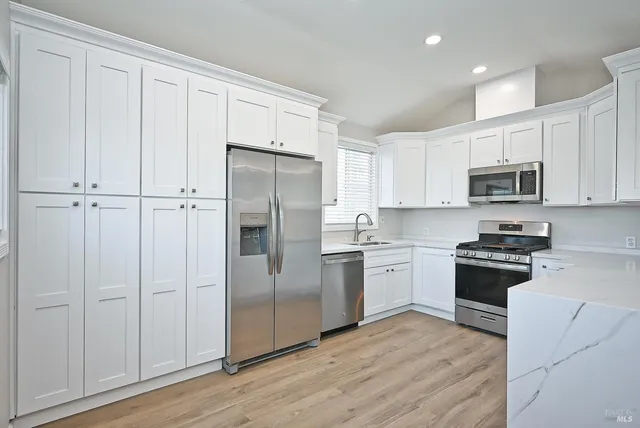 a kitchen with cabinets stainless steel appliances a sink and a hard wood floor