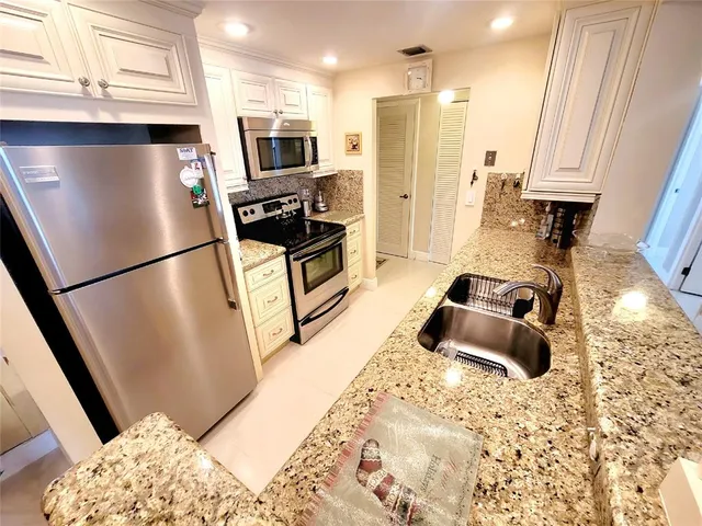 a kitchen with stainless steel appliances granite countertop a refrigerator a stove a sink and a microwave