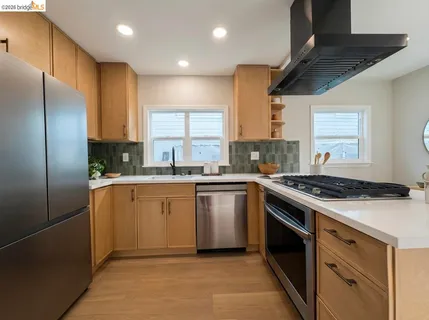 a kitchen with stainless steel appliances granite countertop a stove a sink dishwasher a refrigerator and white cabinets with wooden floor