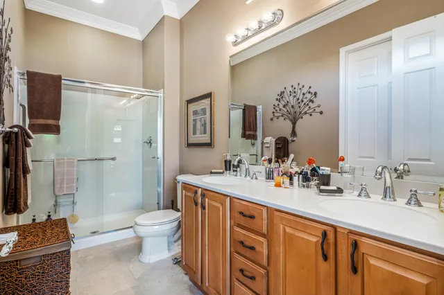 a spacious bathroom with double sink a toilet a mirror and shower