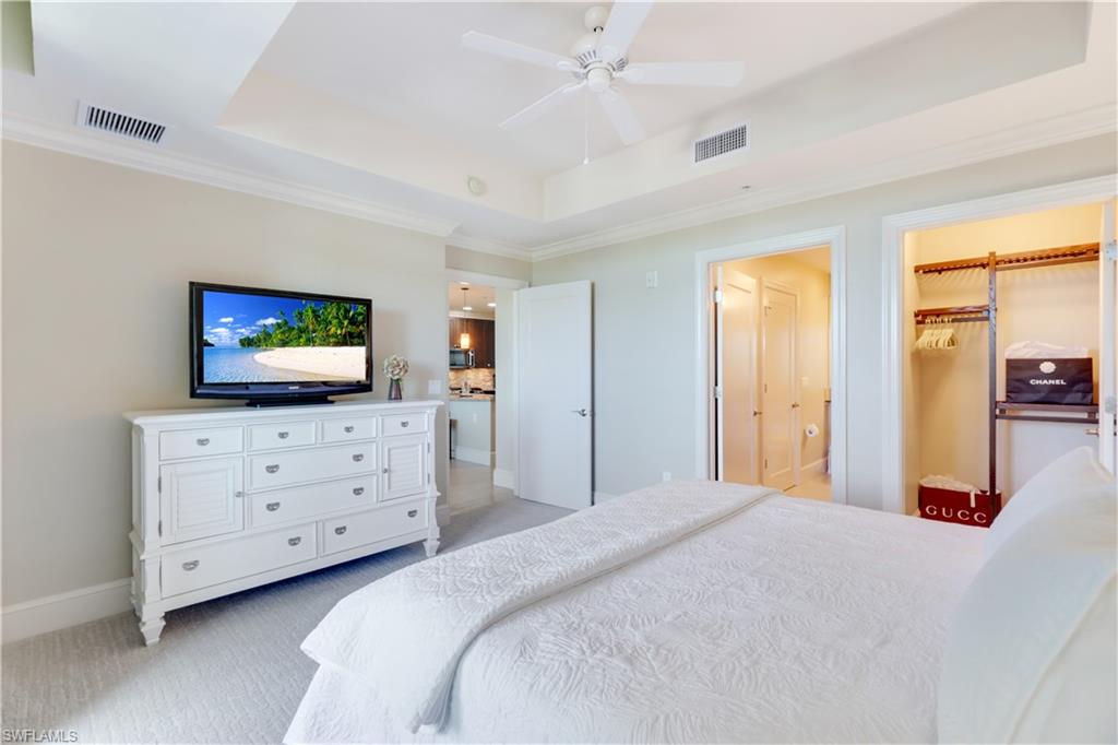 9115 Strada Place, Unit 5205 Naples, FL 34108 - Photo 13 of 36 a bedroom with a bed a dresser and a television