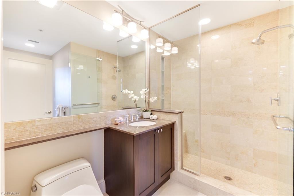 9115 Strada Place, Unit 5205 Naples, FL 34108 - Photo 18 of 36 a bathroom with a sink a toilet a mirror and shower