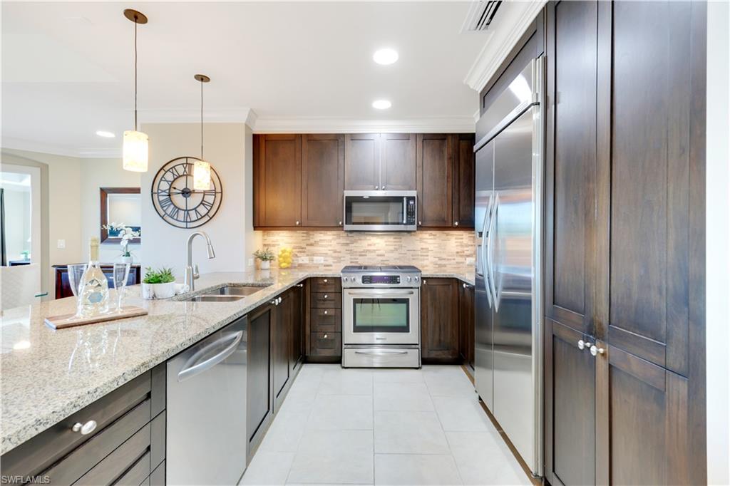 9115 Strada Place, Unit 5205 Naples, FL 34108 - Photo 2 of 36 a kitchen with stainless steel appliances granite countertop a sink a stove a refrigerator and a wooden floors