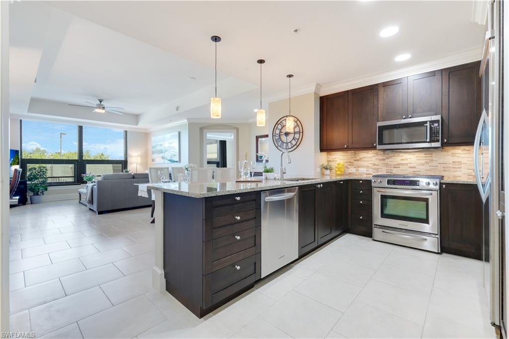 9115 Strada Place, Unit 5205 Naples, FL 34108 - Photo 8 of 36 a large kitchen with a large counter top a sink stainless steel appliances and cabinets