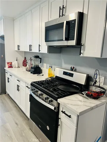 a kitchen with stainless steel appliances granite countertop white cabinets a stove a sink and dishwasher