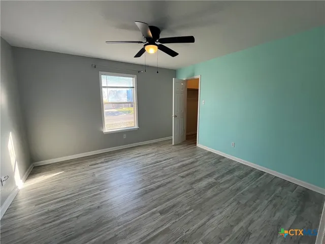 a view of empty room with wooden floor and fan
