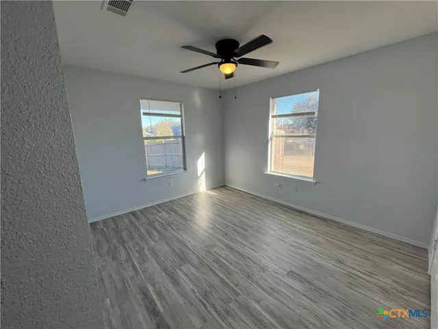 a view of an empty room with wooden floor and a window