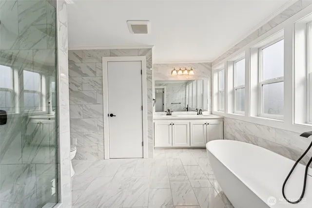 a bathroom with a tub a sink a mirror and a shower