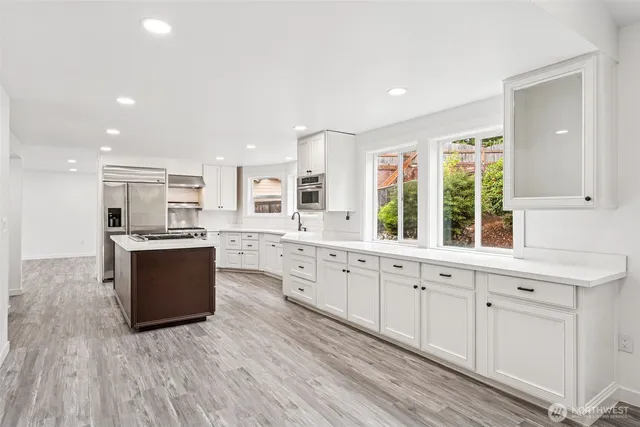 a large kitchen with kitchen island granite countertop a large window and white cabinets