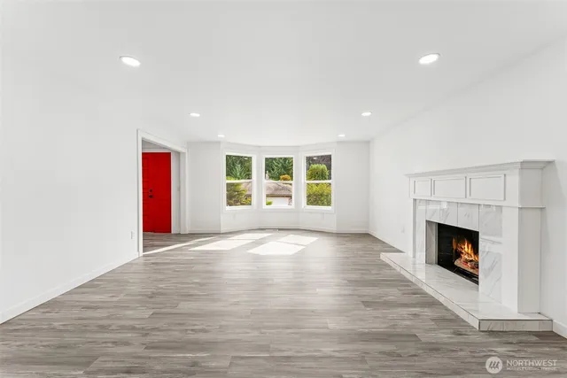 a view of an empty room with wooden floor fireplace and a window