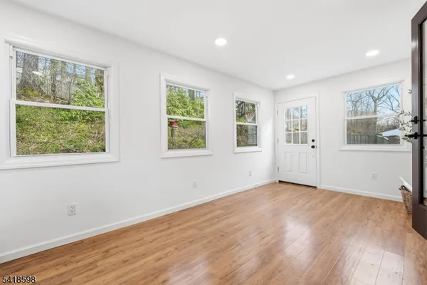 a view of an empty room with a window and wooden floor
