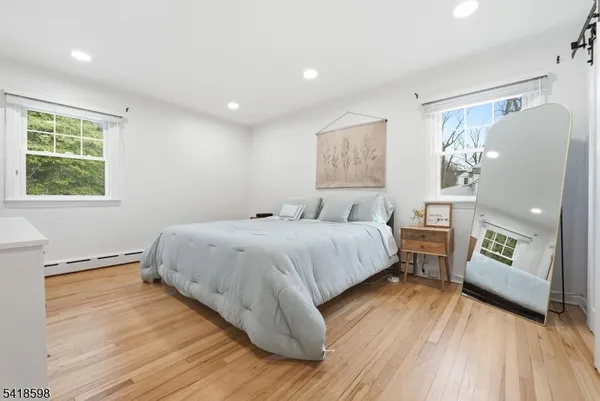 a bedroom with a bed and a dresser with wooden floor