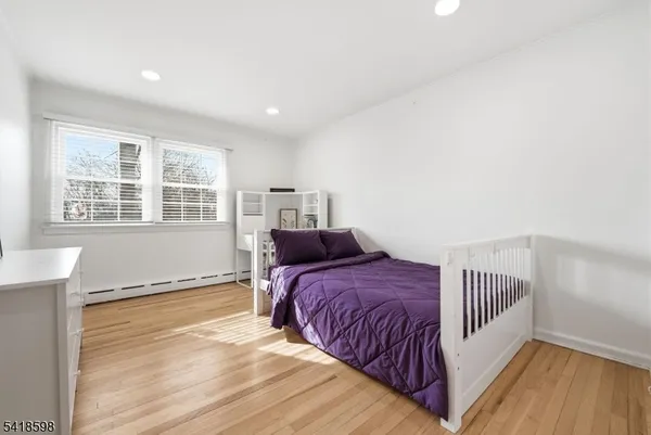 a spacious bedroom with a bed and wooden floor