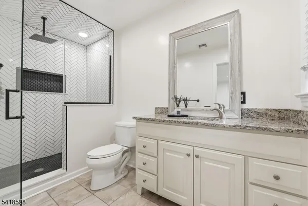 a bathroom with a granite countertop sink a toilet and a mirror