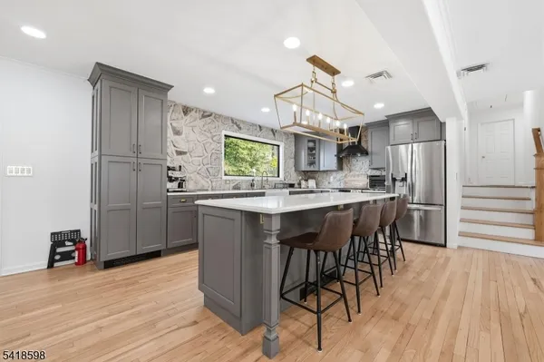 a kitchen with stainless steel appliances kitchen island granite countertop a refrigerator a stove a microwave oven a dining table and chairs with wooden floor