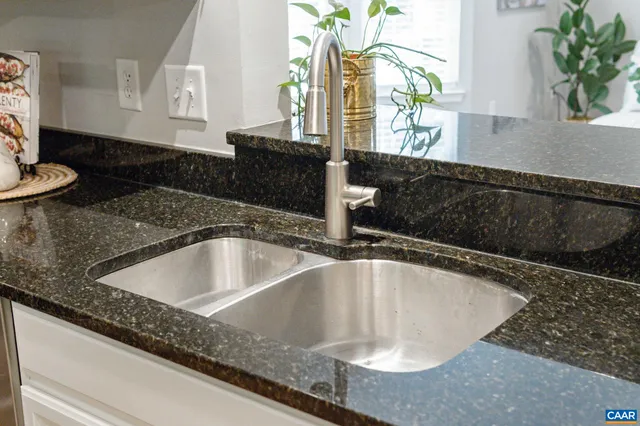 a view of a brick house with a yard plants and a large tree