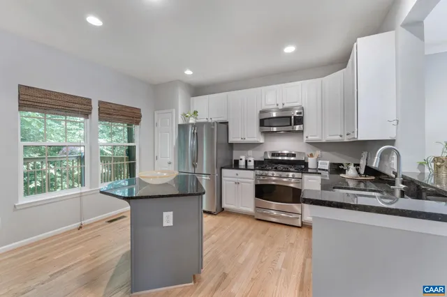 a kitchen with stainless steel appliances granite countertop a refrigerator a sink dishwasher a stove and a refrigerator