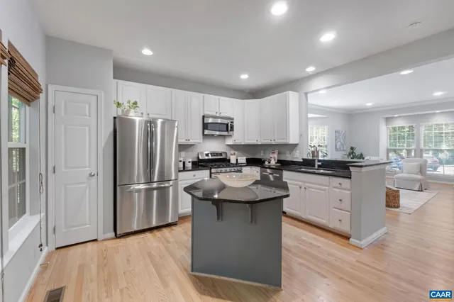 a kitchen with center island stainless steel appliances and wooden floor