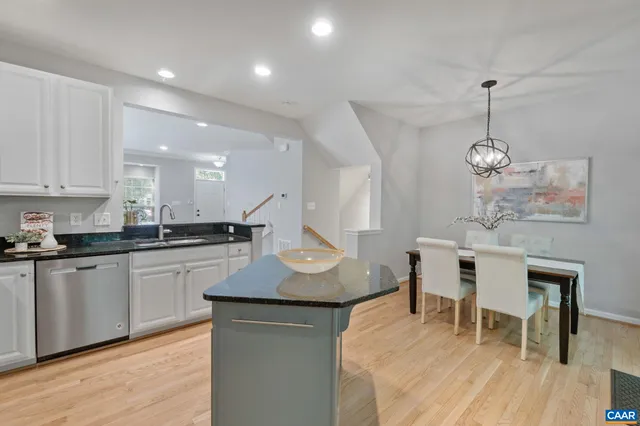 a kitchen with stainless steel appliances granite countertop a refrigerator a sink dishwasher a stove and white cabinets with wooden floor