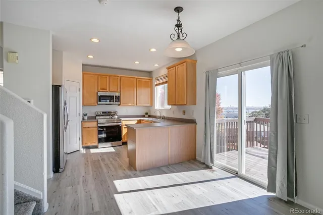 a kitchen with stainless steel appliances kitchen island granite countertop a refrigerator a sink a stove and white cabinets with wooden floor