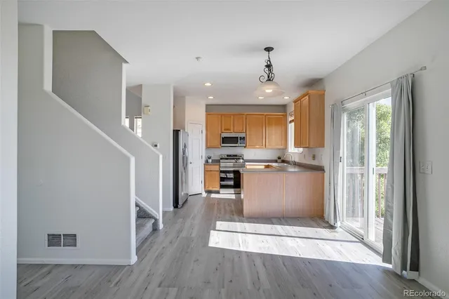 a view of kitchen with kitchen island wooden floor and refrigerator
