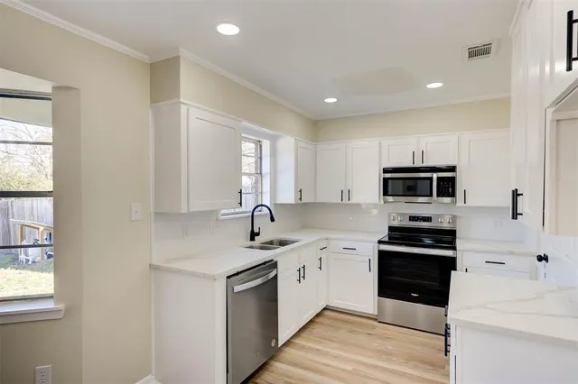 a kitchen with a sink white cabinets and stainless steel appliances