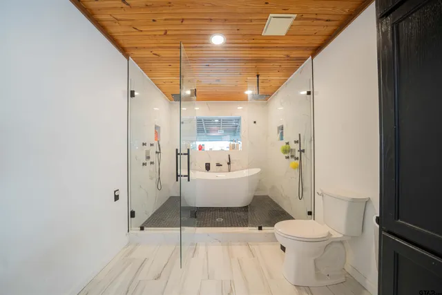 a spacious bathroom with a white tub shower and a toilet
