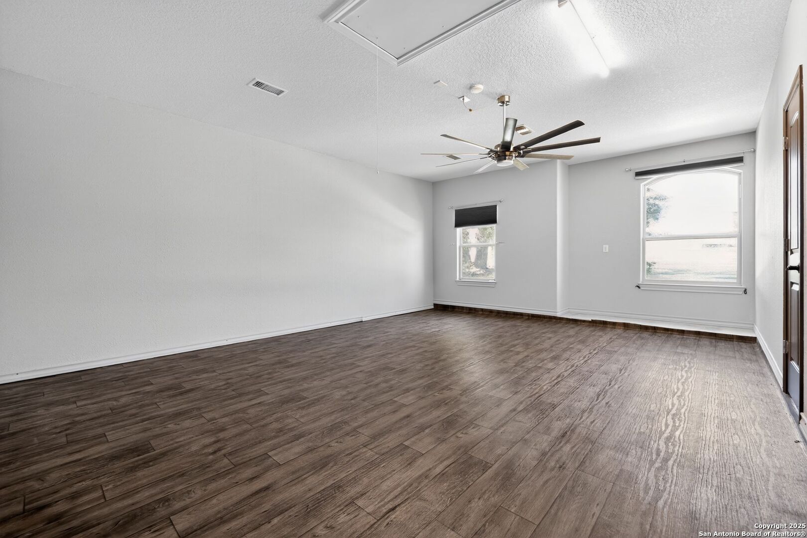 101 Lucky Bandera, TX 78003 - Photo 16 of 42 an empty room with wooden floor chandelier fan and windows