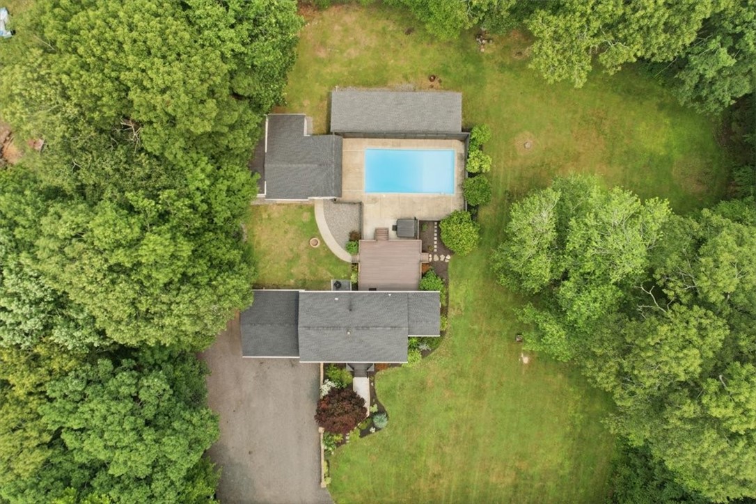 214 Anan Wade Road Glocester, RI 02857 - Photo 6 of 50 The aerial photographs showcase the impressive layout of the property: the main home and attached two-car garage, expansive rear entertainment deck, 17' x 35' in-ground saltwater pool, 2022 six-person hot tub, detached pool house/garage structure, extensive storage areas, and broad grassy yard—all arranged into distinct yet connected spaces.