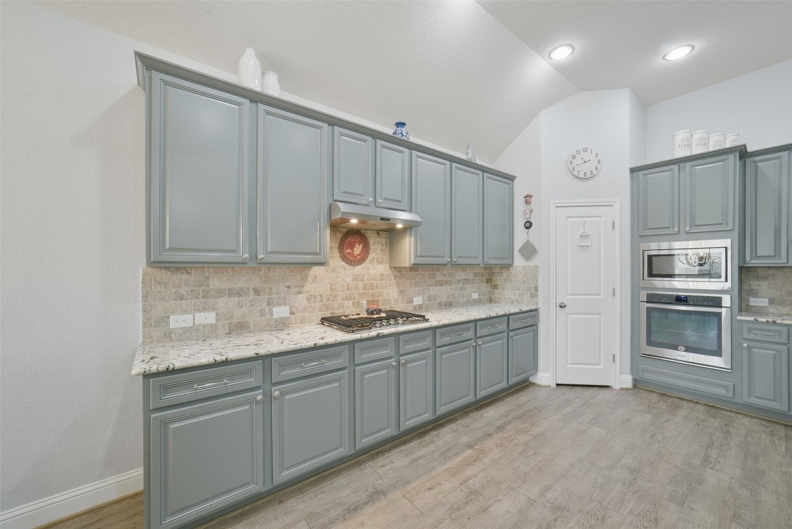 30014 Valley Terrace Drive Fulshear, TX 77406 - Photo 16 of 35 a kitchen with kitchen island granite countertop white cabinets and stainless steel appliances