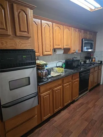 a kitchen with granite countertop wooden cabinets stainless steel appliances and a window
