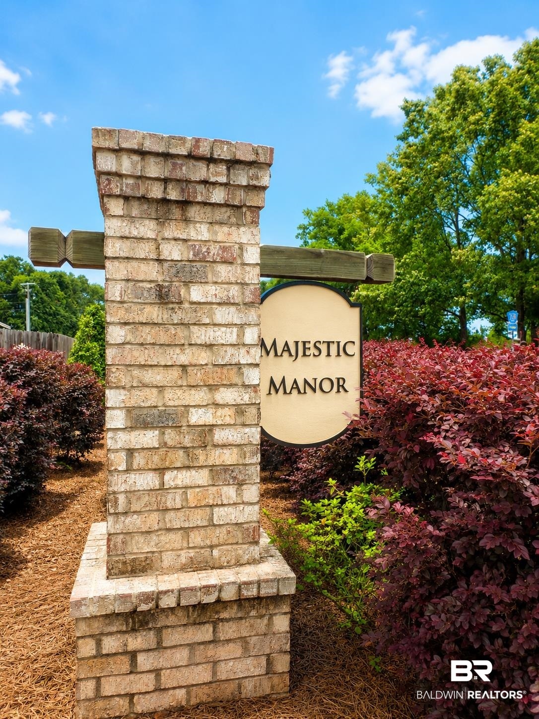 1097 Stella Road Foley, AL 36535 - Photo 14 of 15 Brick entrance column featuring a decorative sign, wood beam accents, and surrounding landscaping