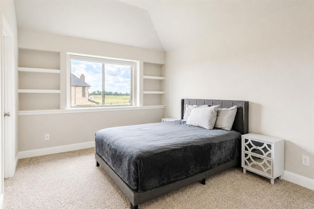 25 Morrison Road Howe, TX 75459 - Photo 20 of 27 Carpeted bedroom featuring a large window with built-in shelving, vaulted ceiling, and baseboard trim