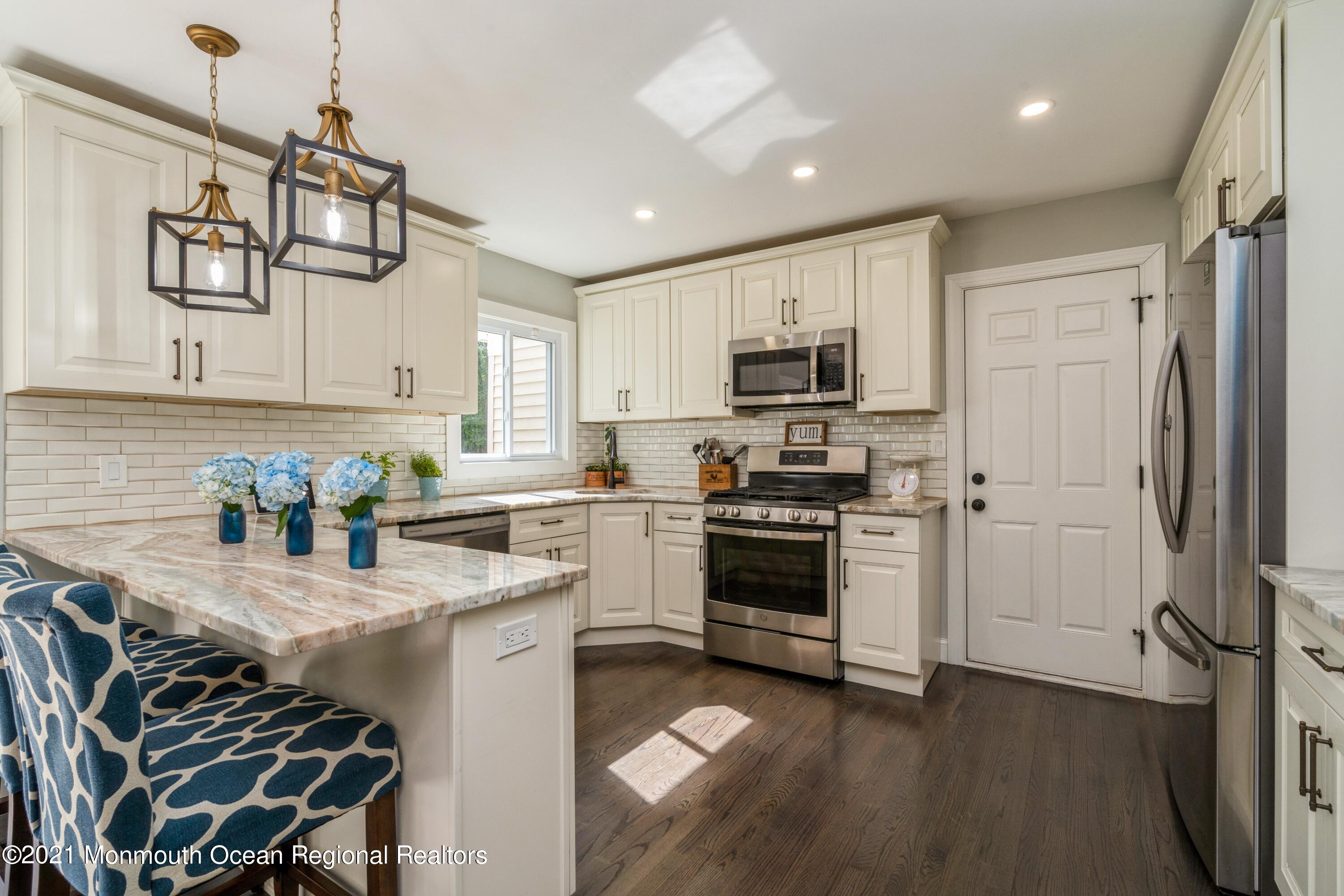 6 Brookside Road Millstone Township, NJ 08510 - Photo 7 of 27 a kitchen with stainless steel appliances a stove a sink a refrigerator white cabinets and wooden floor