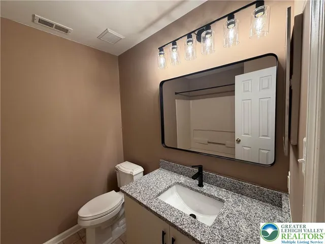a bathroom with a granite countertop sink a mirror and a toilet