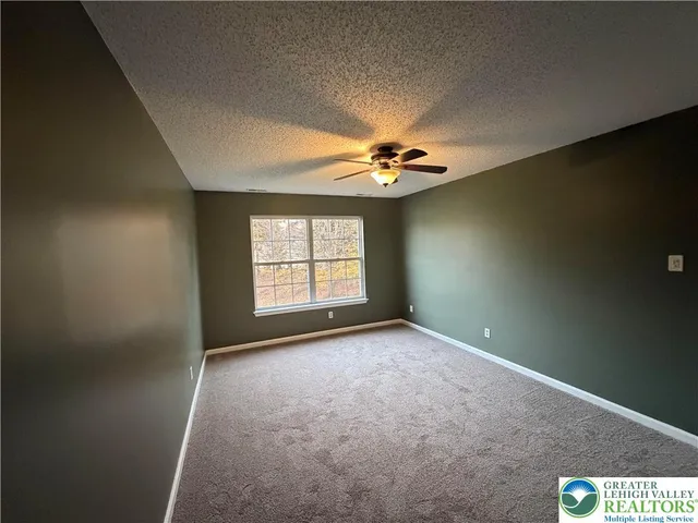 an empty room with windows and chandelier fan