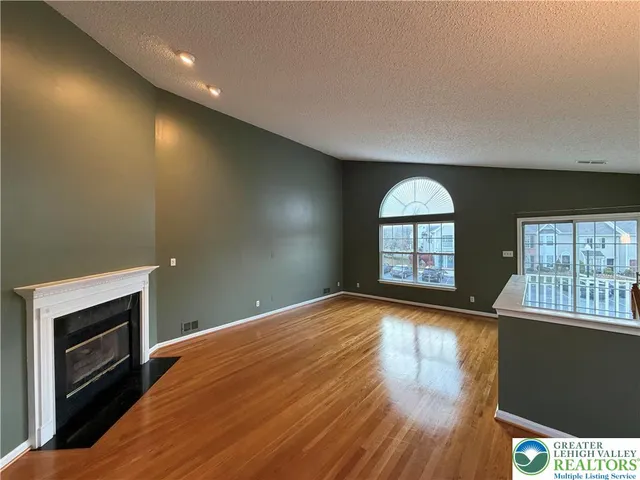 a view of empty room with wooden floor and fireplace