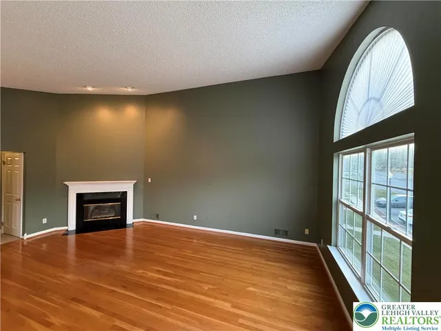 an empty room with wooden floor cabinet and windows