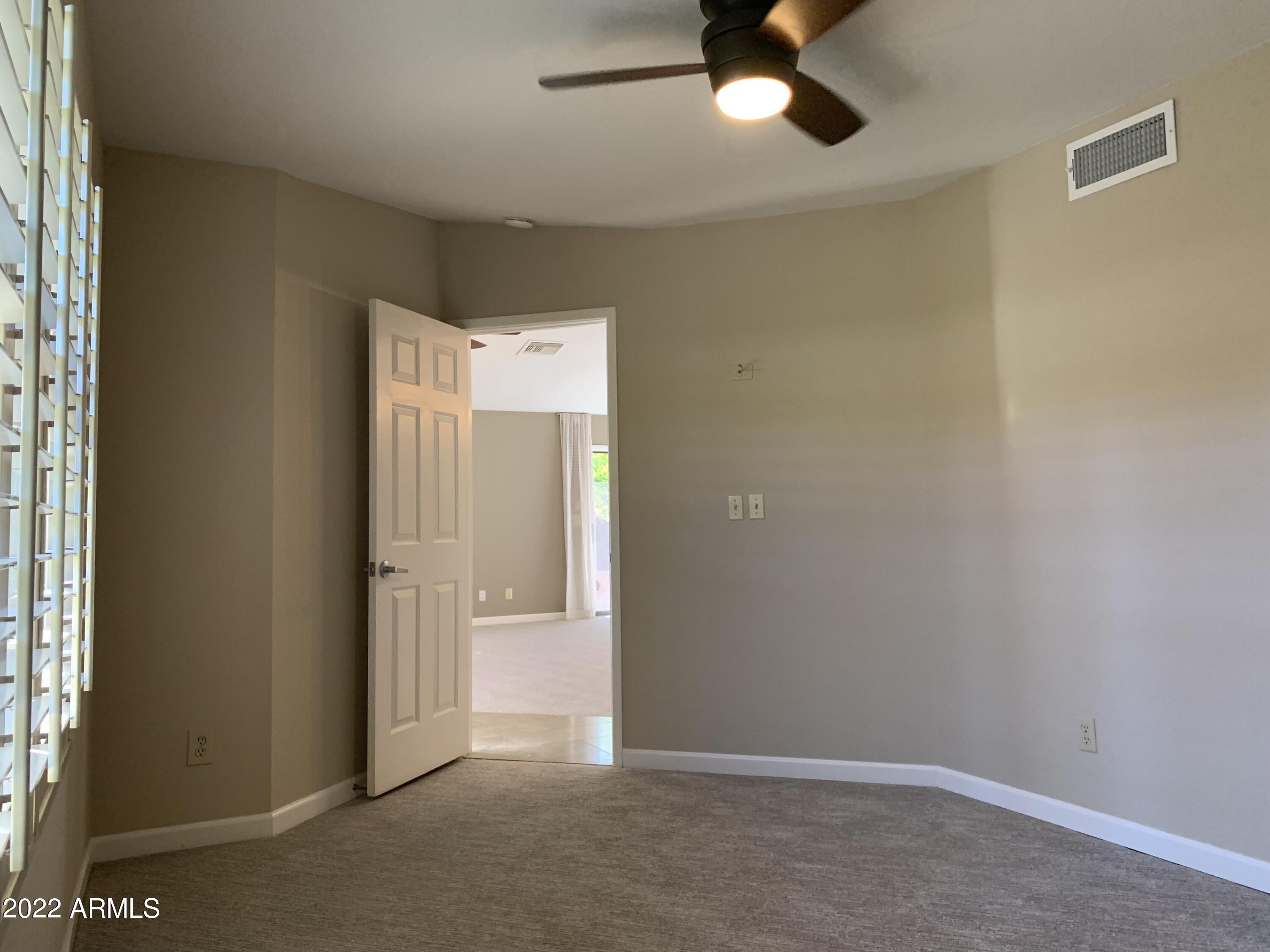 4302 East Bannock Street Phoenix, AZ 85044 - Photo 31 of 55 an empty room with a ceiling fan and carpet