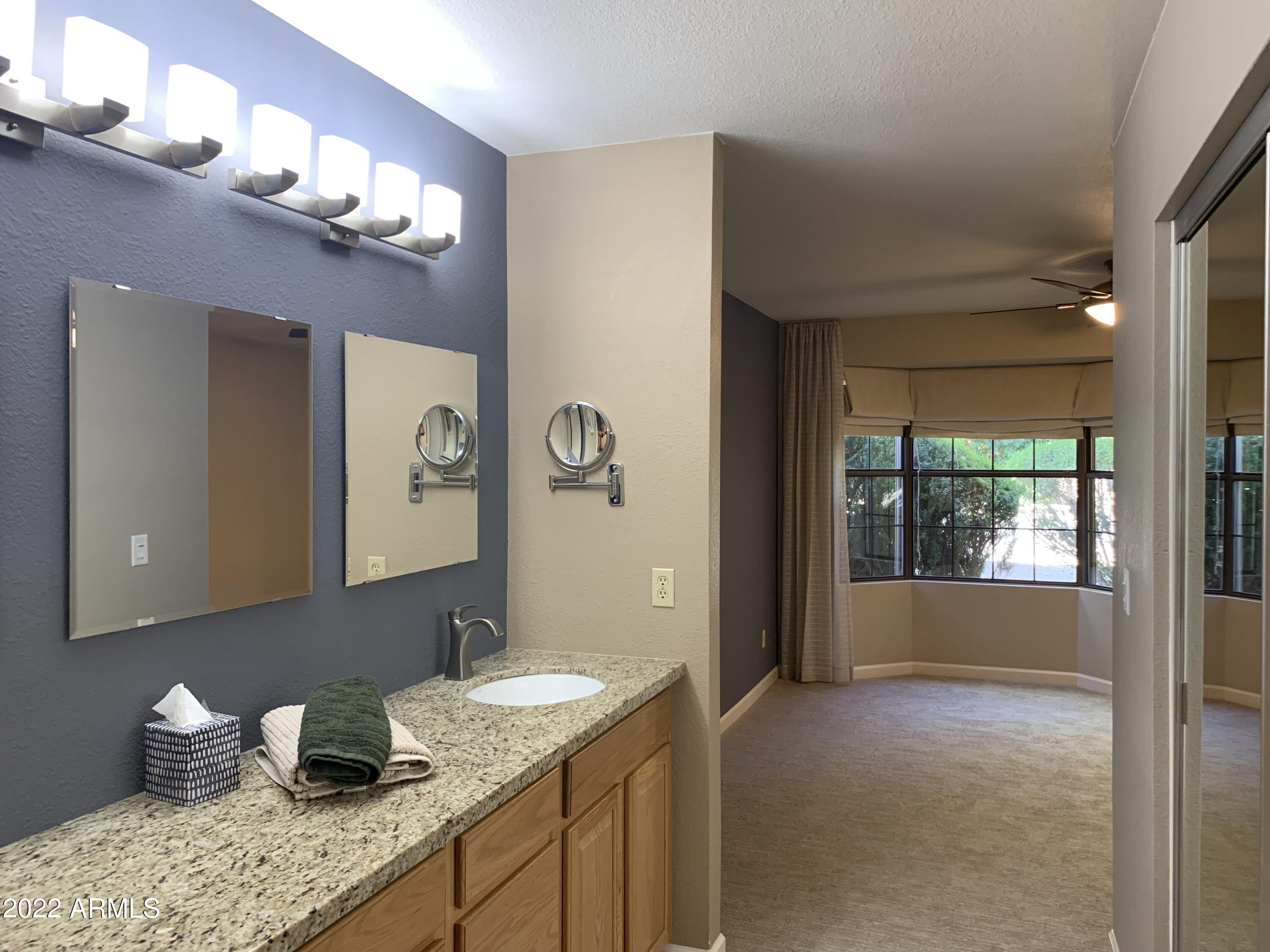 4302 East Bannock Street Phoenix, AZ 85044 - Photo 42 of 55 a bathroom with a granite countertop sink a toilet and a large mirror