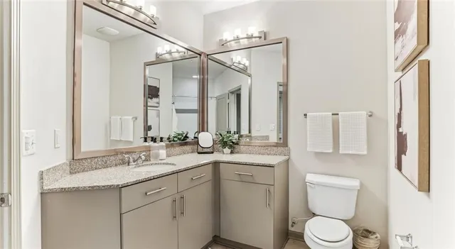 a bathroom with a granite countertop sink mirror vanity and toilet