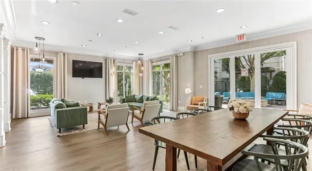 a living room with furniture two large window and wooden floor