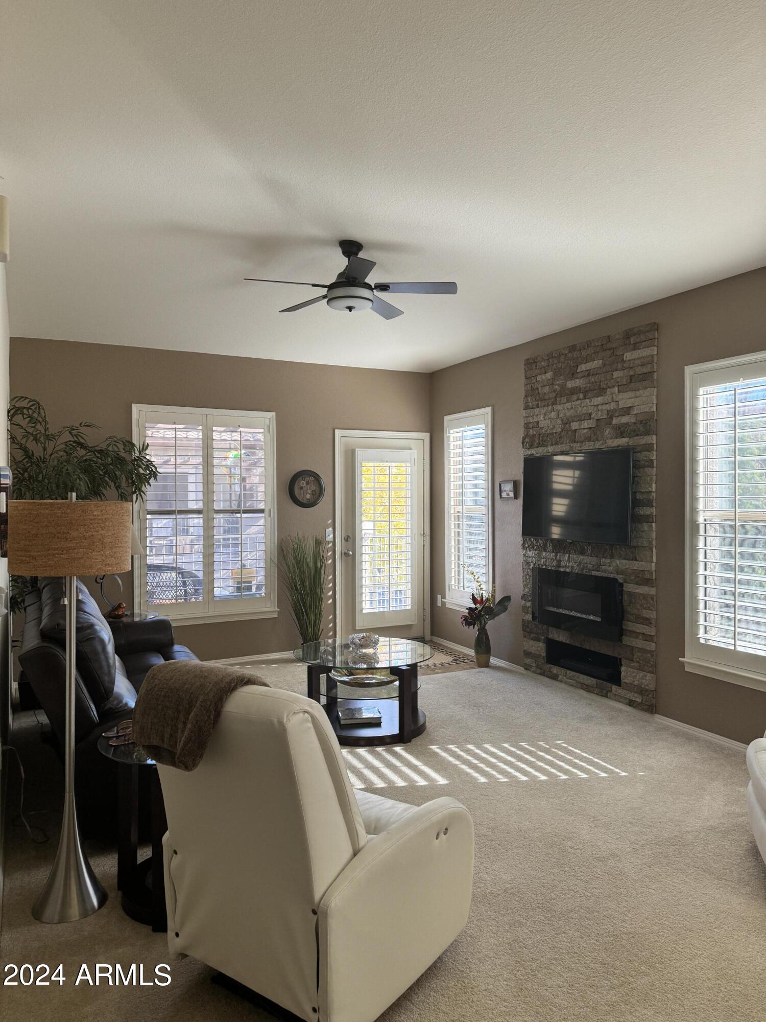 14250 West Wigwam Boulevard, Unit 1421 Litchfield Park, AZ 85340 - Photo 2 of 15 a living room with furniture a flat screen tv and a fireplace