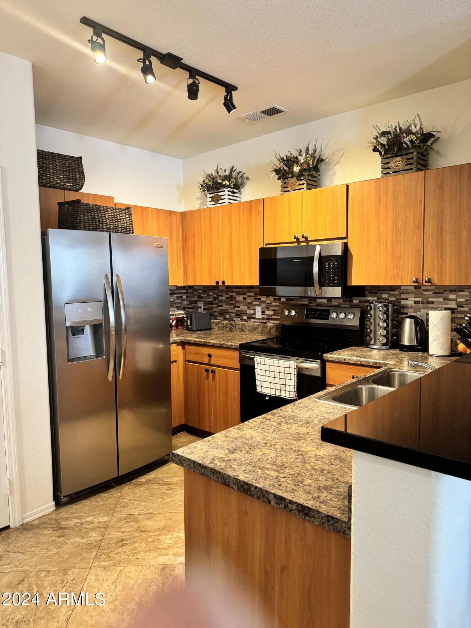 14250 West Wigwam Boulevard, Unit 1421 Litchfield Park, AZ 85340 - Photo 6 of 15 a kitchen with stainless steel appliances granite countertop a sink a stove and a refrigerator