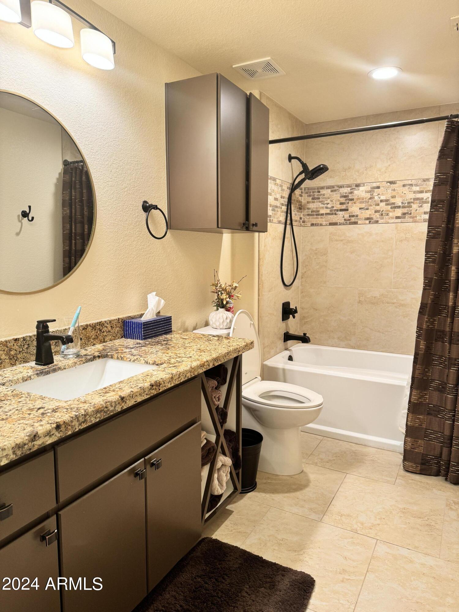 14250 West Wigwam Boulevard, Unit 1421 Litchfield Park, AZ 85340 - Photo 10 of 15 a bathroom with a granite countertop sink toilet and shower
