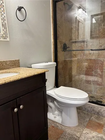 a bathroom with a granite countertop sink toilet and a mirror